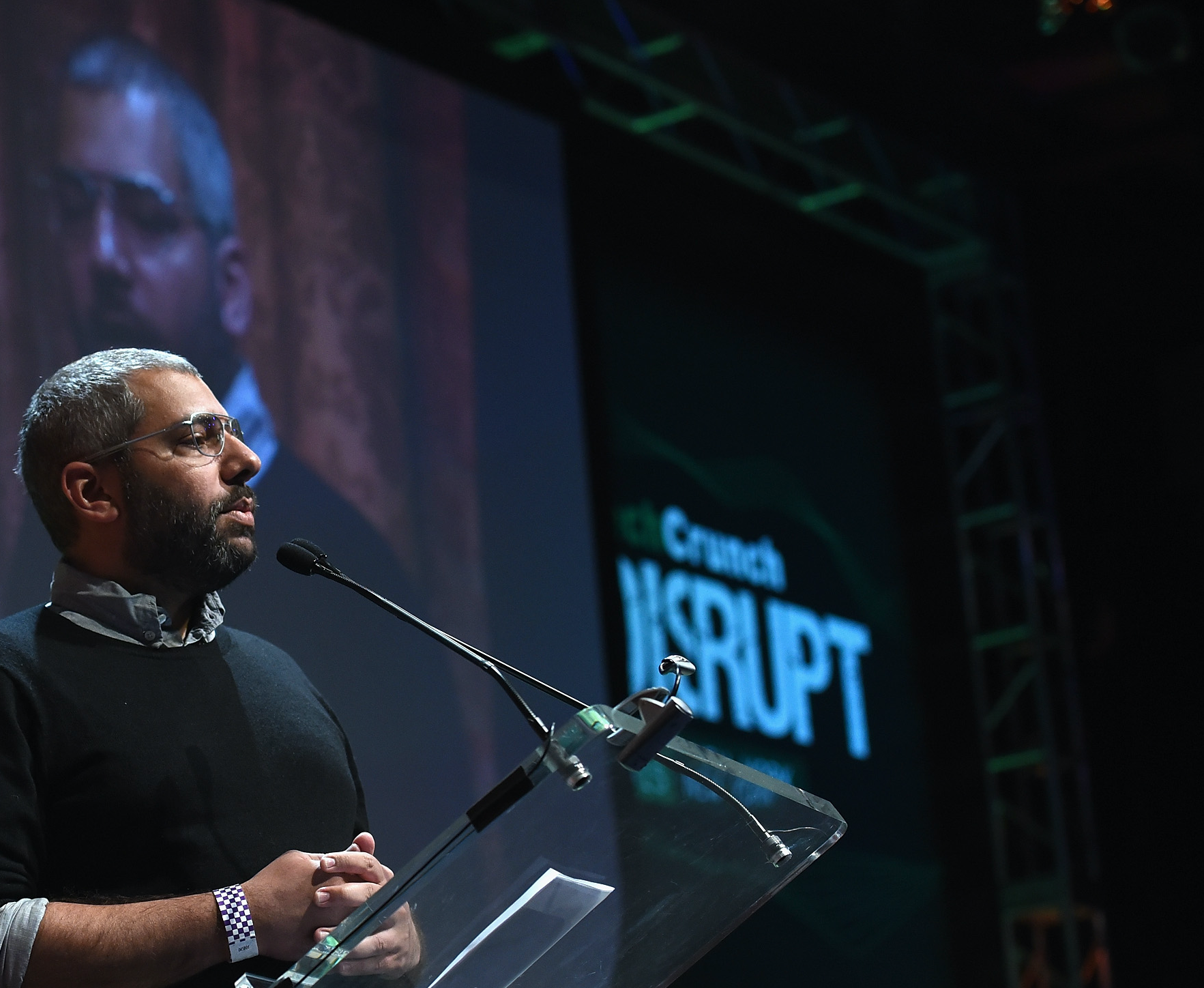 Tarikh Korula speaking onstage at a lectern
